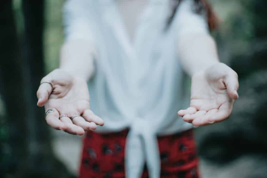 Woman giving hands to the camera offering help on a natural parade, light image